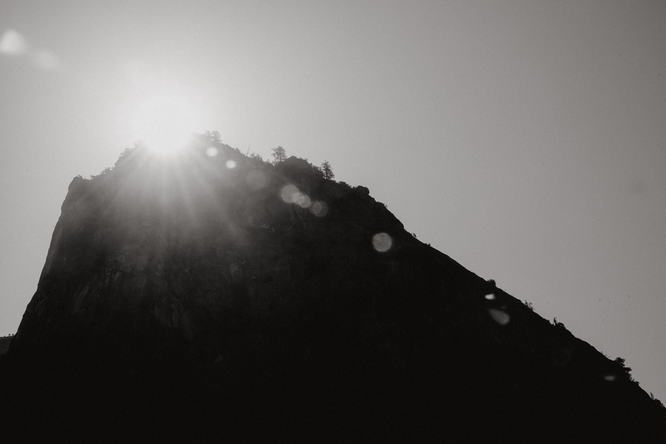 Silhouette of a mountain peak with sunlight shining from behind, creating a dramatic contrast against the sky.