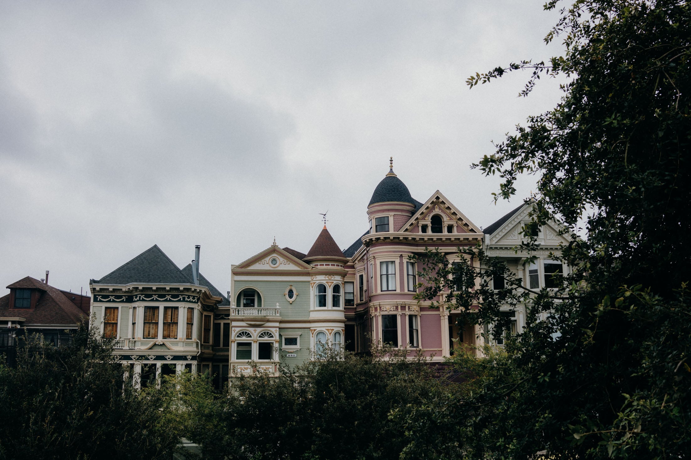 A row of colorful Victorian-style houses with intricate architectural details against a cloudy sky.