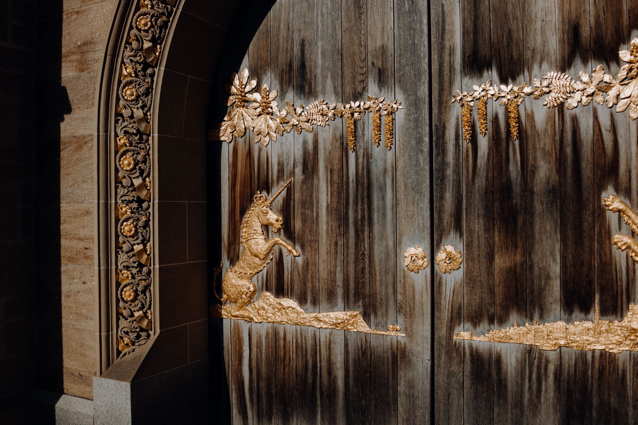 Close-up of an ornate wooden door featuring intricate golden carvings, including a unicorn and floral designs.