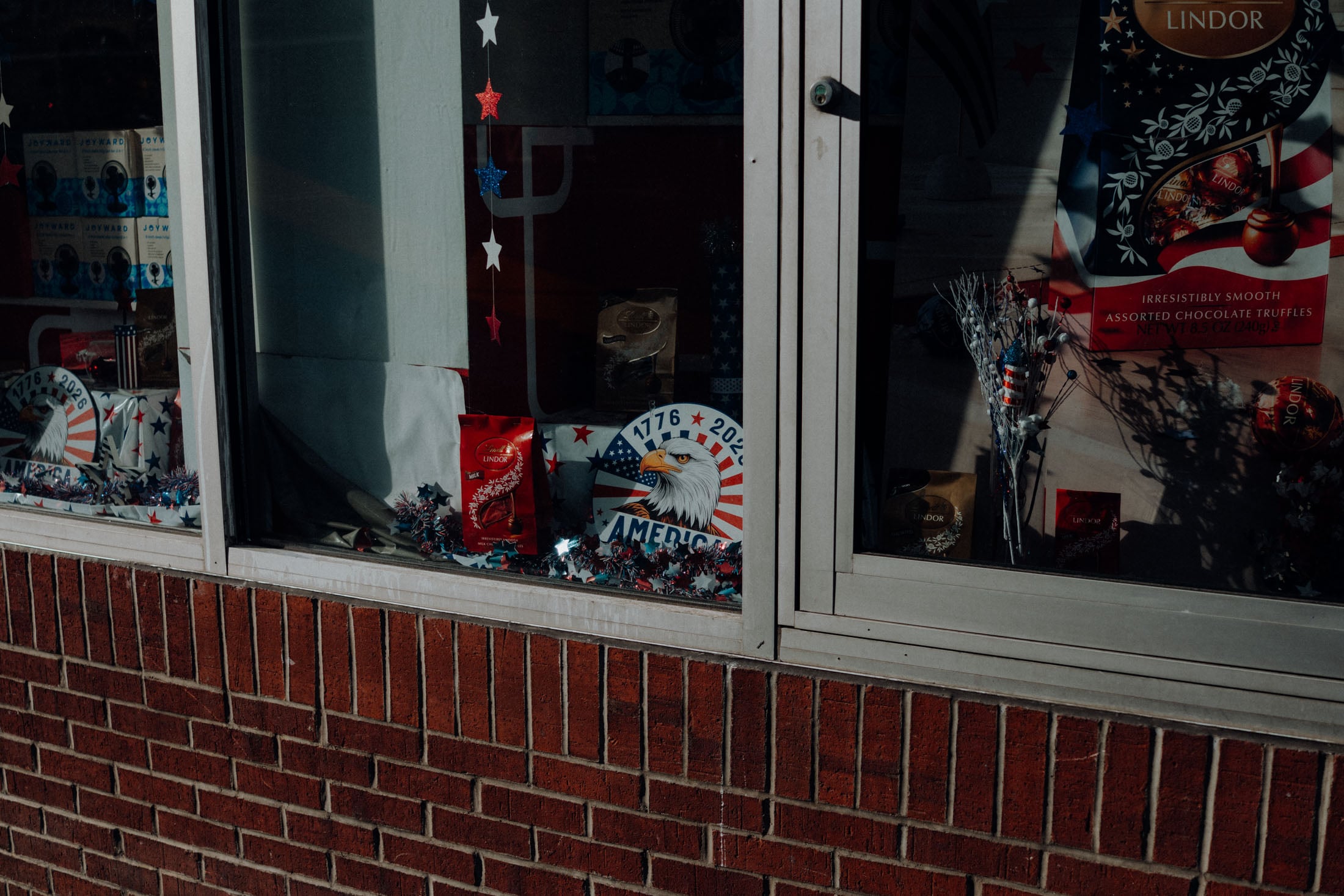 Window display featuring patriotic decorations, including an eagle emblem, red, white, and blue stars, and assorted chocolate truffles.